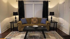 A living room with a sofa, two side tables with lamps, a coffee table, and a patterned rug. - Tyler's Texas Rose, a beautiful 2BR/1BA house with back yard (Tyler)