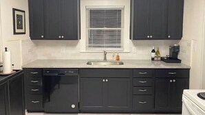 A kitchen with dark cabinets, a white countertop, a sink, and a window with blinds. - Tyler's Texas Rose, a beautiful 2BR/1BA house with back yard (Tyler)