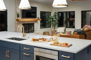 A modern kitchen with a large island, built-in appliances, and a fireplace.