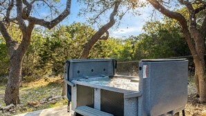 A hot tub with a bench, surrounded by trees and a clear sky.