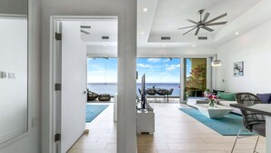 Un amplio salón con vista al mar, ventilador de techo y diseño interior moderno.
