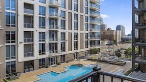 Un moderno edificio de apartamentos con piscina en la azotea, varios balcones y vistas a la ciudad.