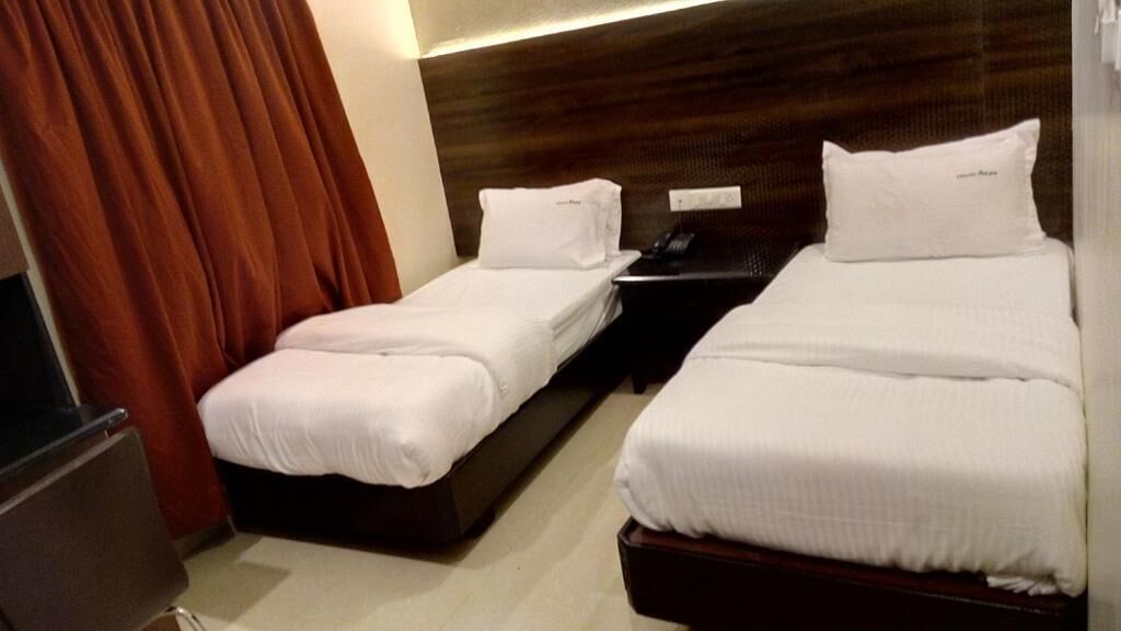 Habitación de hotel con dos camas individuales, un escritorio y una silla.