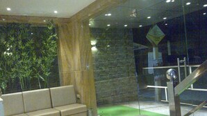 A modern lobby with a stone wall, a green carpet, and a seating area with a sofa. - HOTEL GRAND PARKWAY (Chennai)