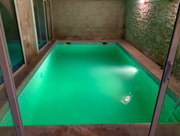 Una piscina coperta rettangolare con acqua cristallina, circondata da pareti e pavimento piastrellato.