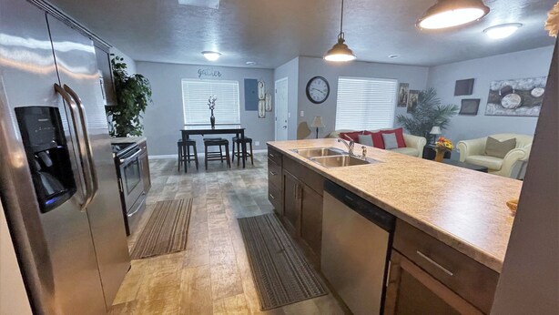 A modern kitchen with a central island, stainless steel appliances, and a dining area with a table and chairs. - Juniper Townhouse #4 (Mitchell)