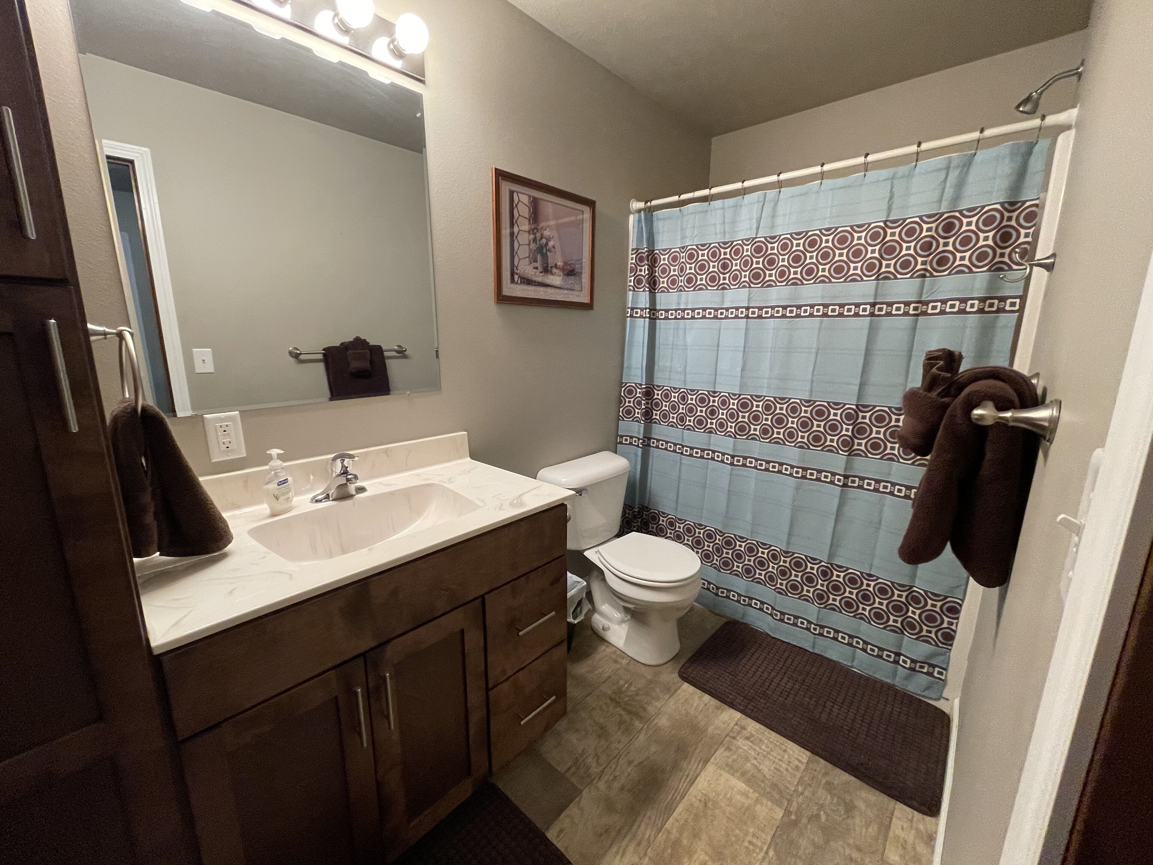 A bathroom with a double sink vanity, a toilet, and a shower curtain with a geometric pattern.