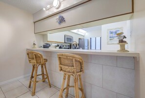 A bathroom with a large mirror, two wicker chairs, a sink, and a towel rack. - Steps to the Beach! Rocket Launch View Condo (Cocoa Beach)