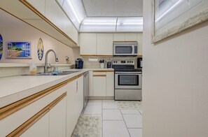 A compact kitchen with a microwave, oven, and sink.