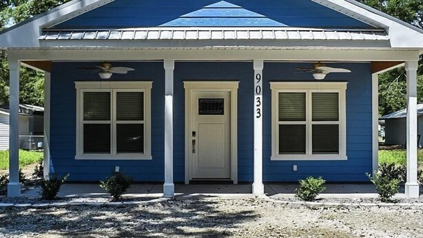 A two-story house with a blue exterior, white trim, and a gabled roof.