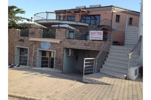 Un edificio a due piani con facciata in pietra, un balcone e una scala che conduce al piano superiore.