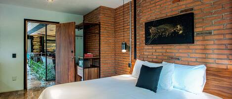 Un dormitorio con una cama grande, una pared de ladrillo y una puerta que da a un balcón.