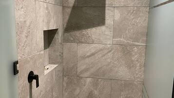 A modern bathroom with a walk-in shower, tiled walls, and a glass partition.