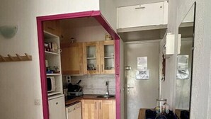 A compact kitchen with wooden cabinets, a microwave, and a sink. - 40m² With Terrace In A Residence With Pool (Le Grau-du-Roi)
