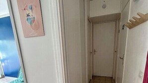 A narrow hallway with tiled flooring, a door at the end, and a small window on the left. - 40m² With Terrace In A Residence With Pool (Le Grau-du-Roi)