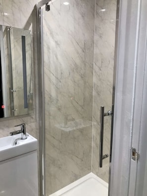 A bathroom with a glass-enclosed shower, a white sink, and a mirror.