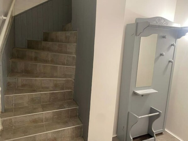 Una escalera con barandilla y una puerta con espejo y una pequeña repisa.