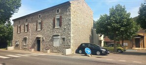Un bâtiment en pierre avec une voiture garée devant.