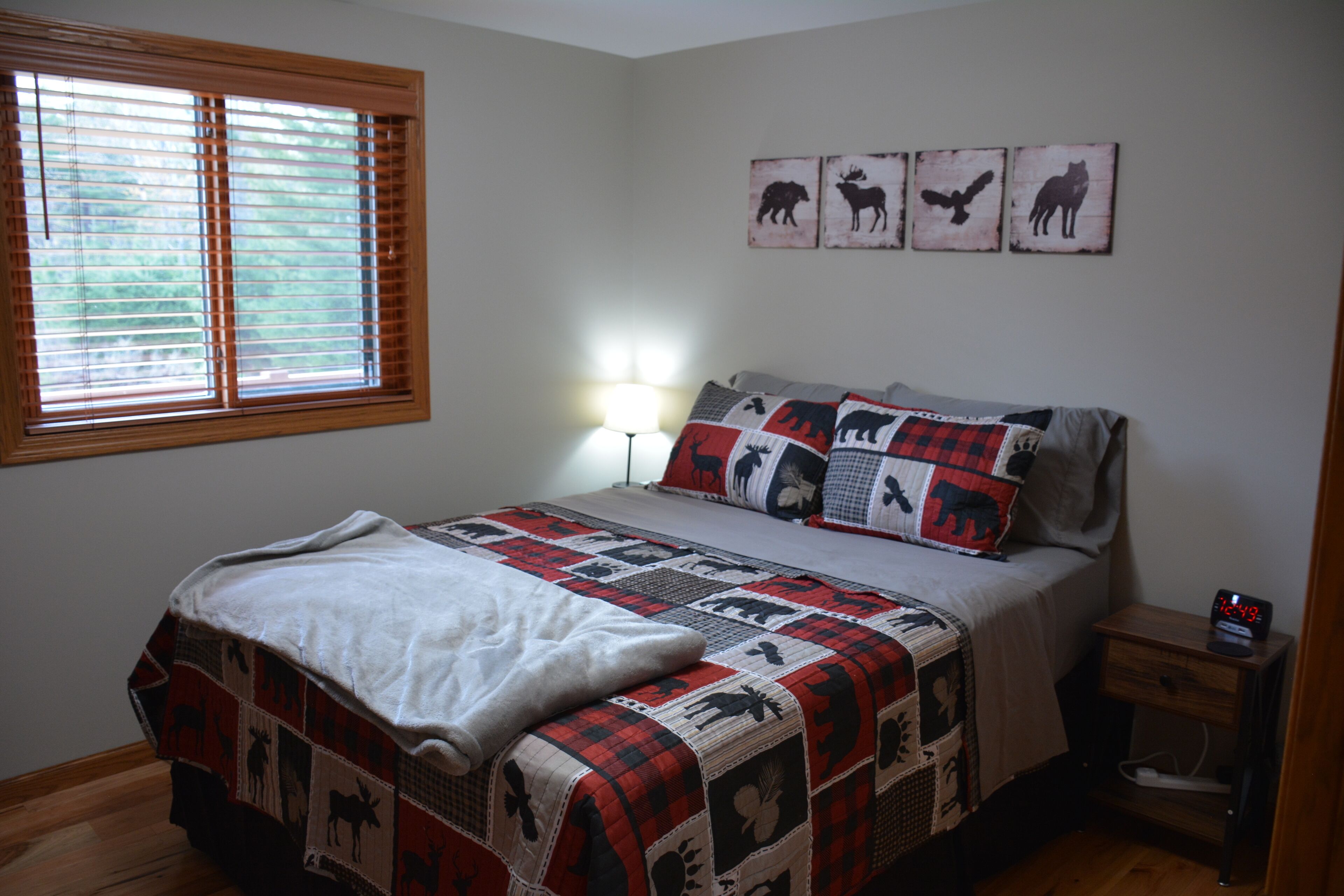 A bedroom with a bed, a bedside table with a lamp, and wall art.