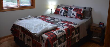 A bedroom with a bed, a bedside table with a lamp, and wall art.