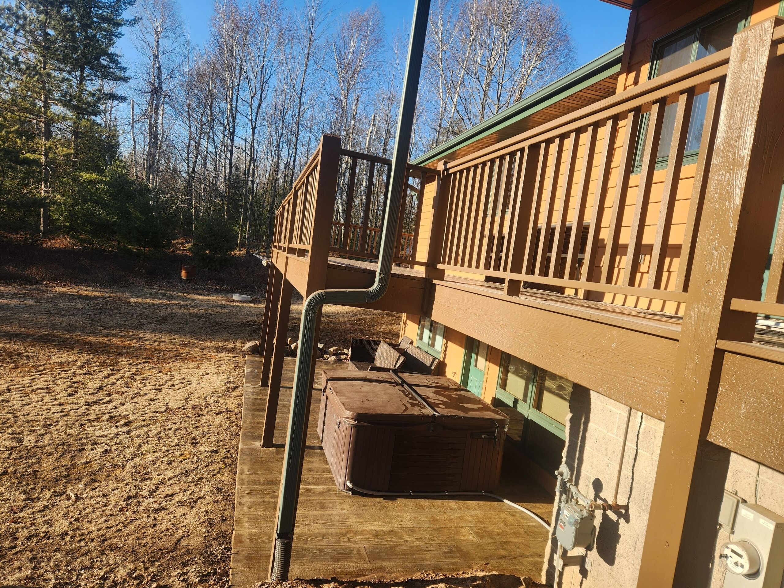 A wooden deck with a bench and a suitcase, overlooking a forested area.