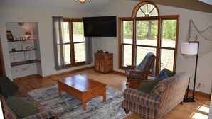 A living room with a wooden coffee table, plaid sofa, and a television.