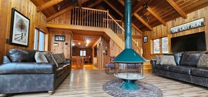 A spacious living area with two leather sofas, a central glass-top table, and a wooden staircase leading to an upper level.