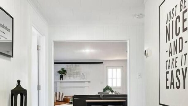 A modern interior with a wooden floor, a dining area with a table and chairs, and a kitchen in the background.
