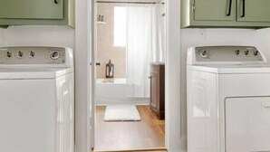 A laundry room with two washing machines and green cabinets.