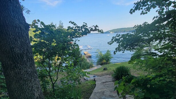A stone pathway leading to a lakeside area with a dock and boats. - Dog Friendly and Beautiful Main Channel View at the 34.5MM in a "NO WAKE" cove.. (Sunrise Beach)