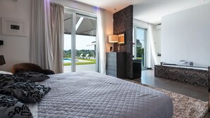 Une chambre avec un grand lit, une vue sur une piscine, une salle de bain avec un meuble-lavabo et un balcon.