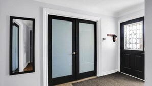 A hallway with a black door, a mirror, and a doorbell. - Niagara Falls Retreat: Walk to the Wonders (Niagara Falls)