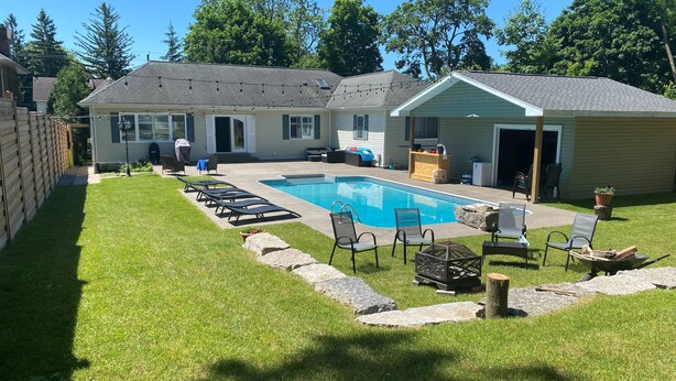 A backyard with a swimming pool, lounge chairs, and a covered patio area. - Niagara Falls Retreat: Walk to the Wonders (Niagara Falls)
