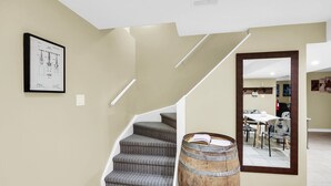 A staircase with grey carpeted steps, a wooden barrel, and a framed technical drawing on the wall. - Niagara Falls Retreat: Walk to the Wonders (Niagara Falls)