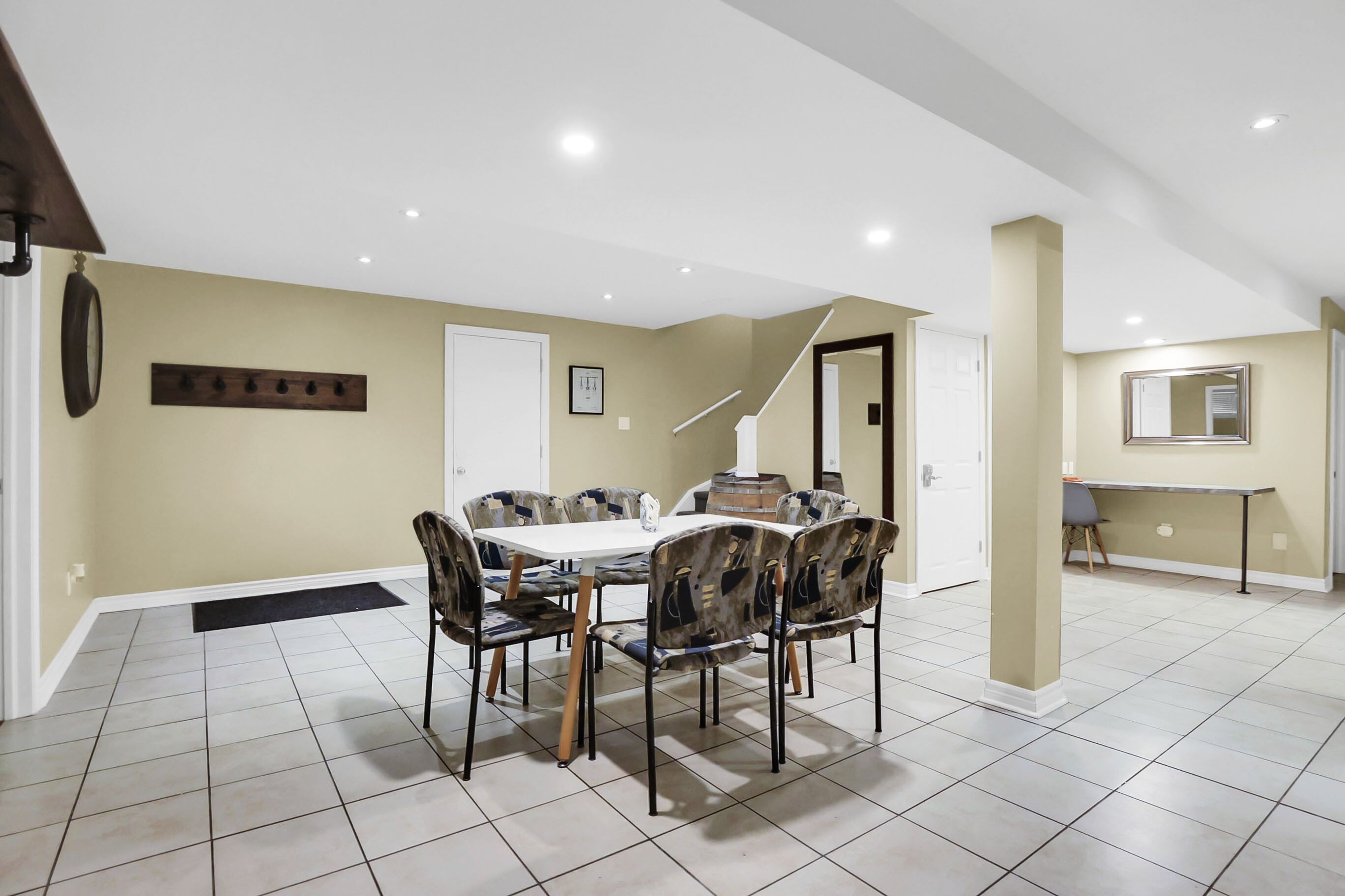 Un coin repas avec une table et des chaises, un porte-manteau et un escalier menant à une autre pièce.