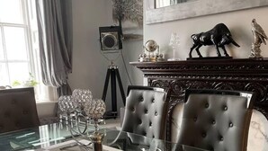 A modern dining room with a glass table, leather chairs, and decorative items. - 5 Bed House - Sleeps 12 - Pets - Parking (Ross-on-Wye)