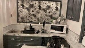 A kitchen with dark cabinets, a marble countertop, a chandelier, and a floral wall mural. - 5 Bed House - Sleeps 12 - Pets - Parking (Ross-on-Wye)