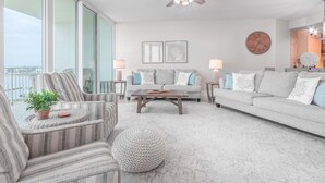 Uma sala de estar moderna com sofá, poltronas, mesa de centro e ventilador de teto.