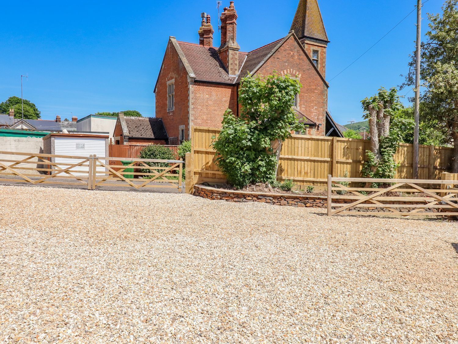 A traditional brick building with a prominent steeple, surrounded by a gravel driveway and wooden fences.
