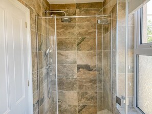 Eine Duschkabine mit Handbrause und am Wand montiertem Wasserhahn.