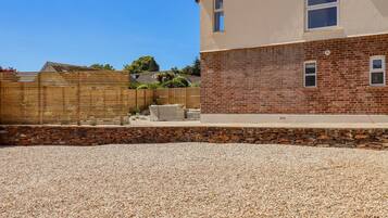 A residential building with a brick facade, a stone retaining wall, and a gravel driveway.