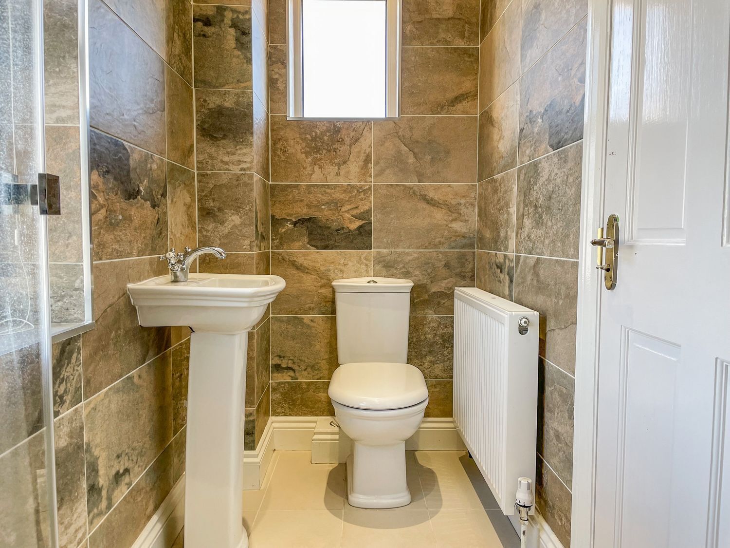Une salle de bain avec un lavabo sur colonne, des toilettes et un radiateur.