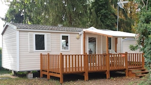 Une maison mobile dotée d’une terrasse en bois et d’un porche couvert.