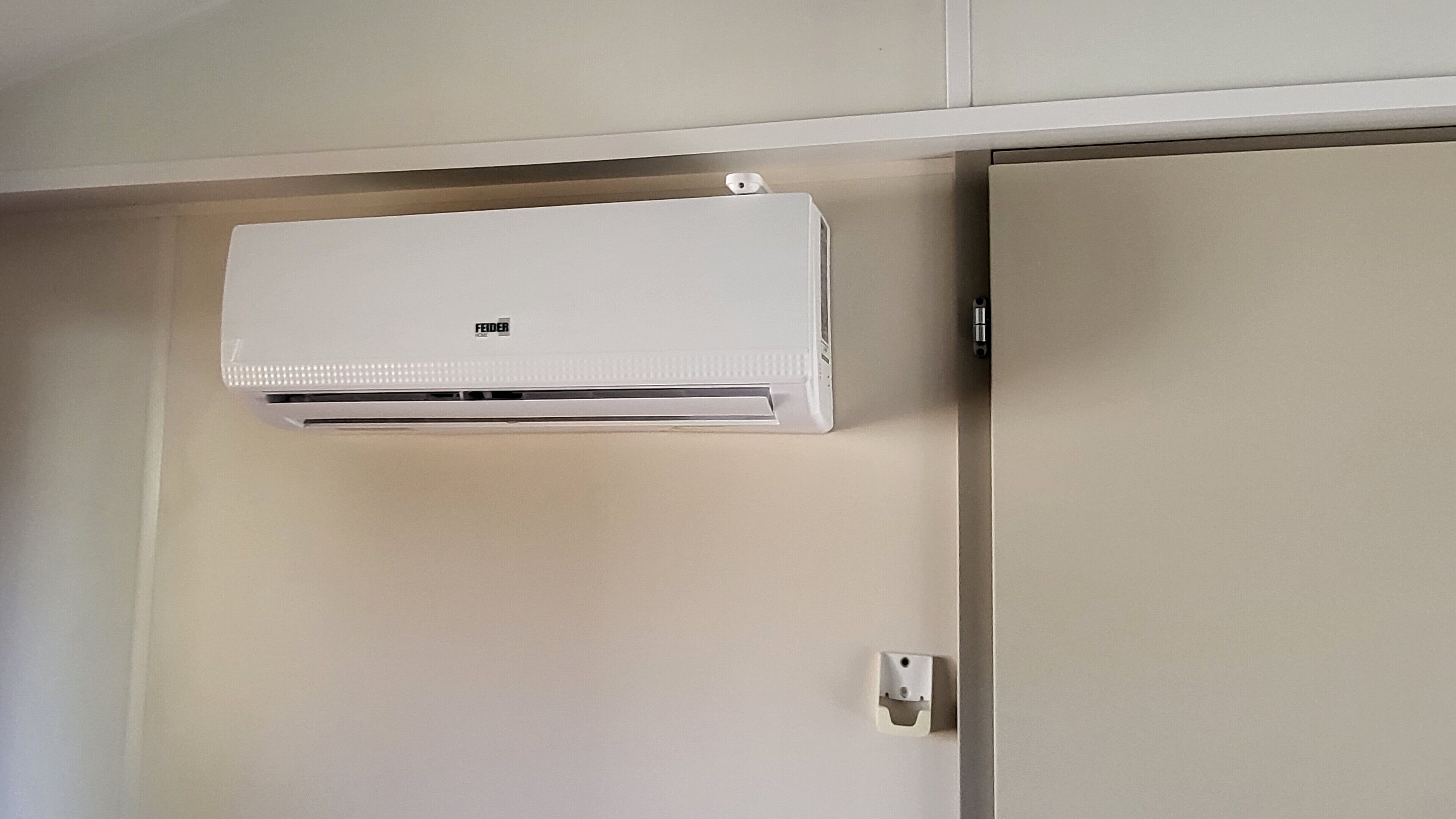 Un equipo de aire acondicionado blanco montado en la pared sobre una puerta.