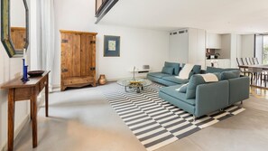 A modern living room with a blue sofa, a wooden cabinet, and a checkered rug.