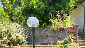A garden with a stone wall, a spherical lamp post, and hydrangea flowers. - Arya's House - wi fi, air conditioning, sea view, parking (Campania)