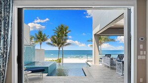 A modern hotel room with a private infinity pool, a beach view, and a seating area with a view of the ocean.