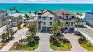 A coastal residential area with multiple houses, a clear blue sky, and the ocean in the background.