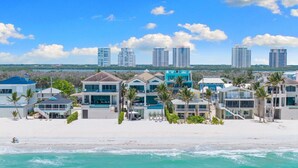 A beachfront property with multiple buildings, including a large house with a balcony and a smaller structure.