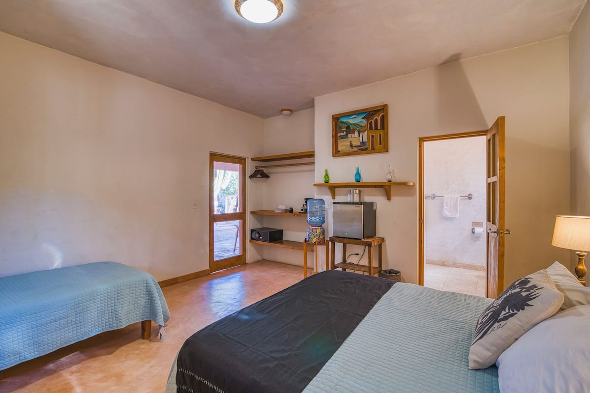 Un dormitorio con dos camas, televisión, dispensador de agua y un cuadro en la pared.